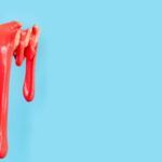 Image of a pink blob of slime being held by a white hand. It's on a blue background